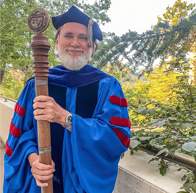 a person in a graduation gown holding a staff