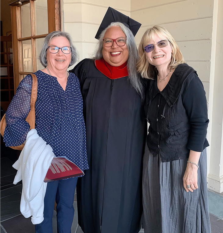 a person in a graduation gown and cap standing next to a person in a doorway