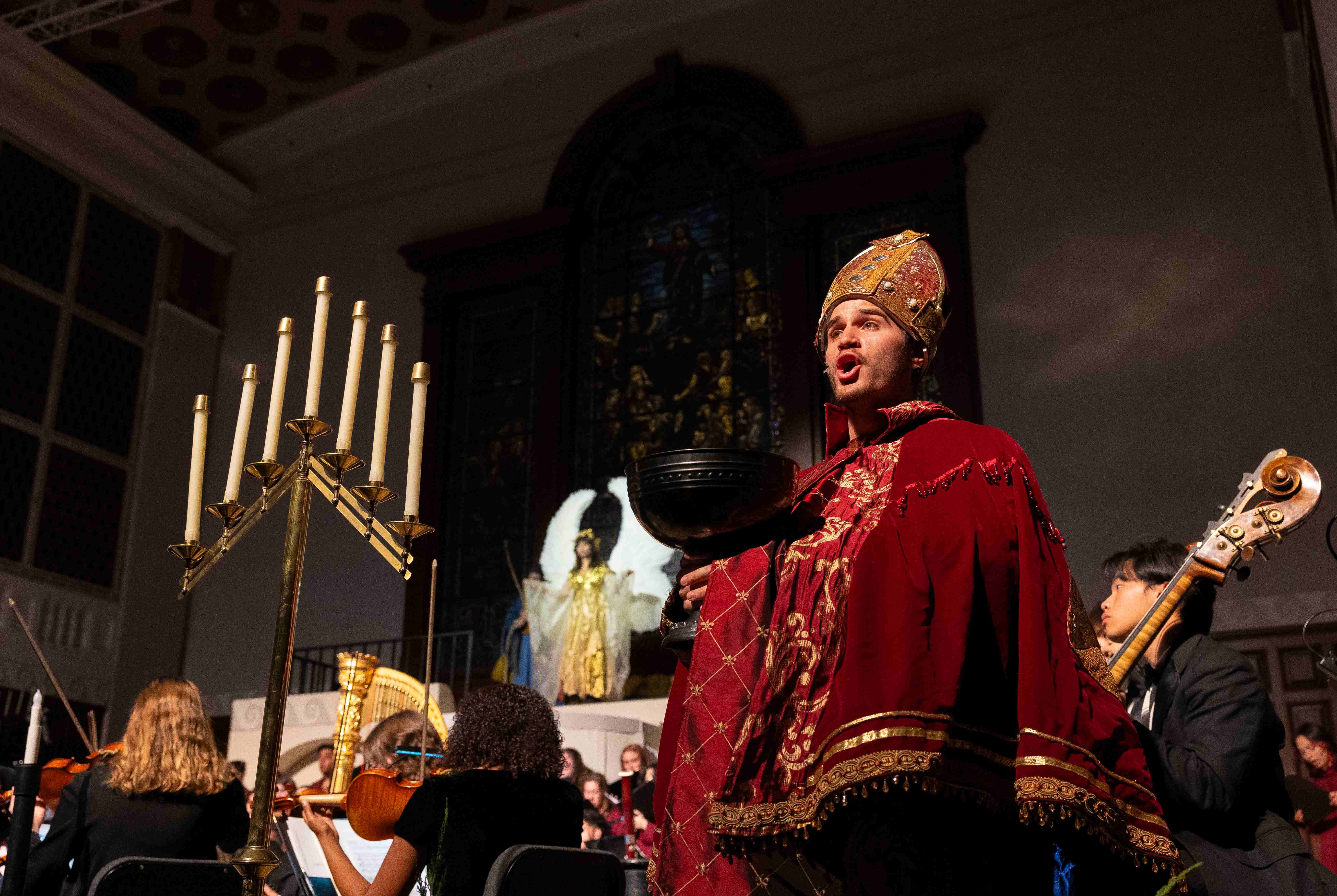 a person in a red robe and gold hat holding a bowl