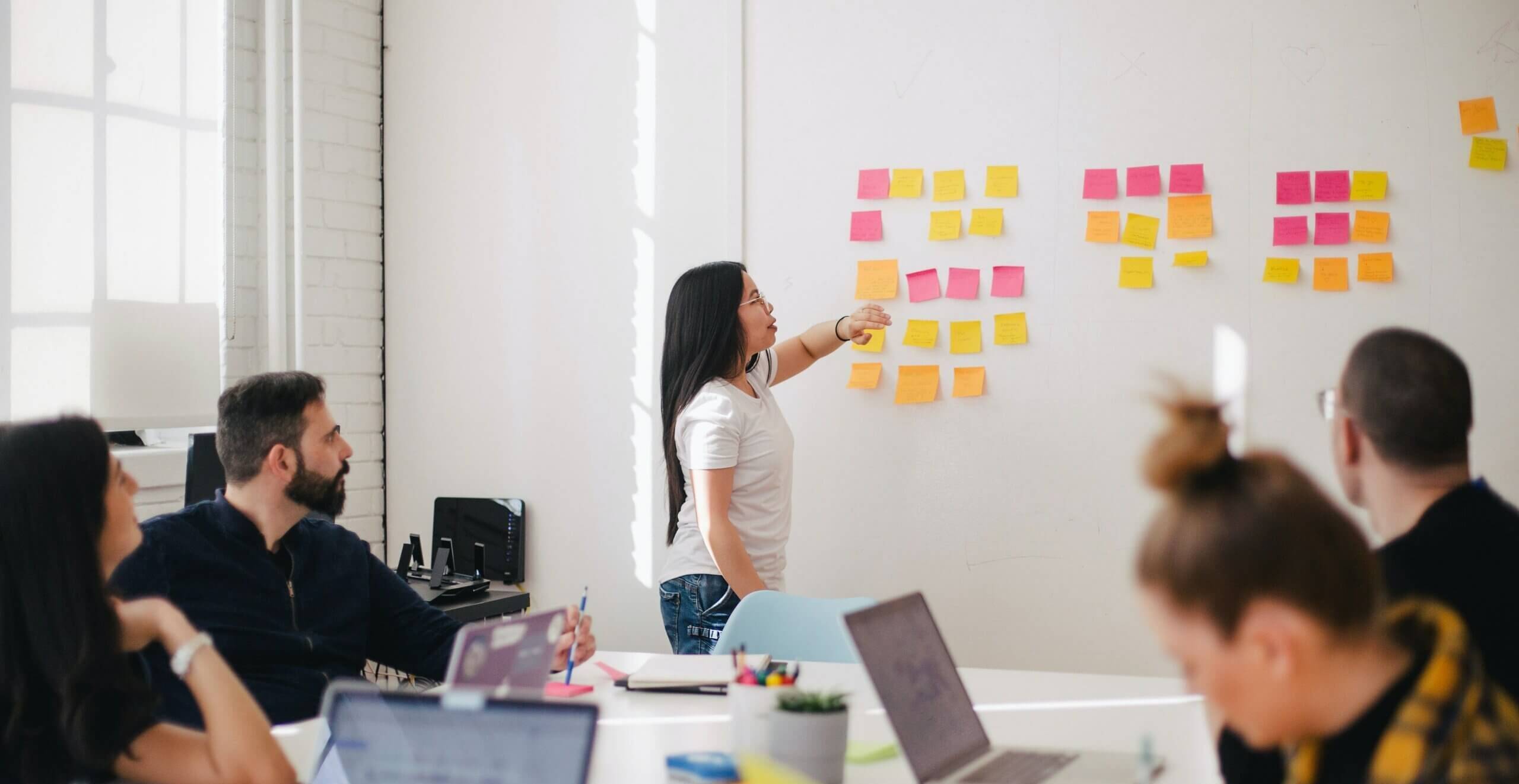 a person pointing at a wall with persony sticky notes
