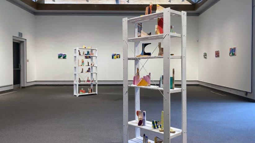 a room with white shelves and art on the wall