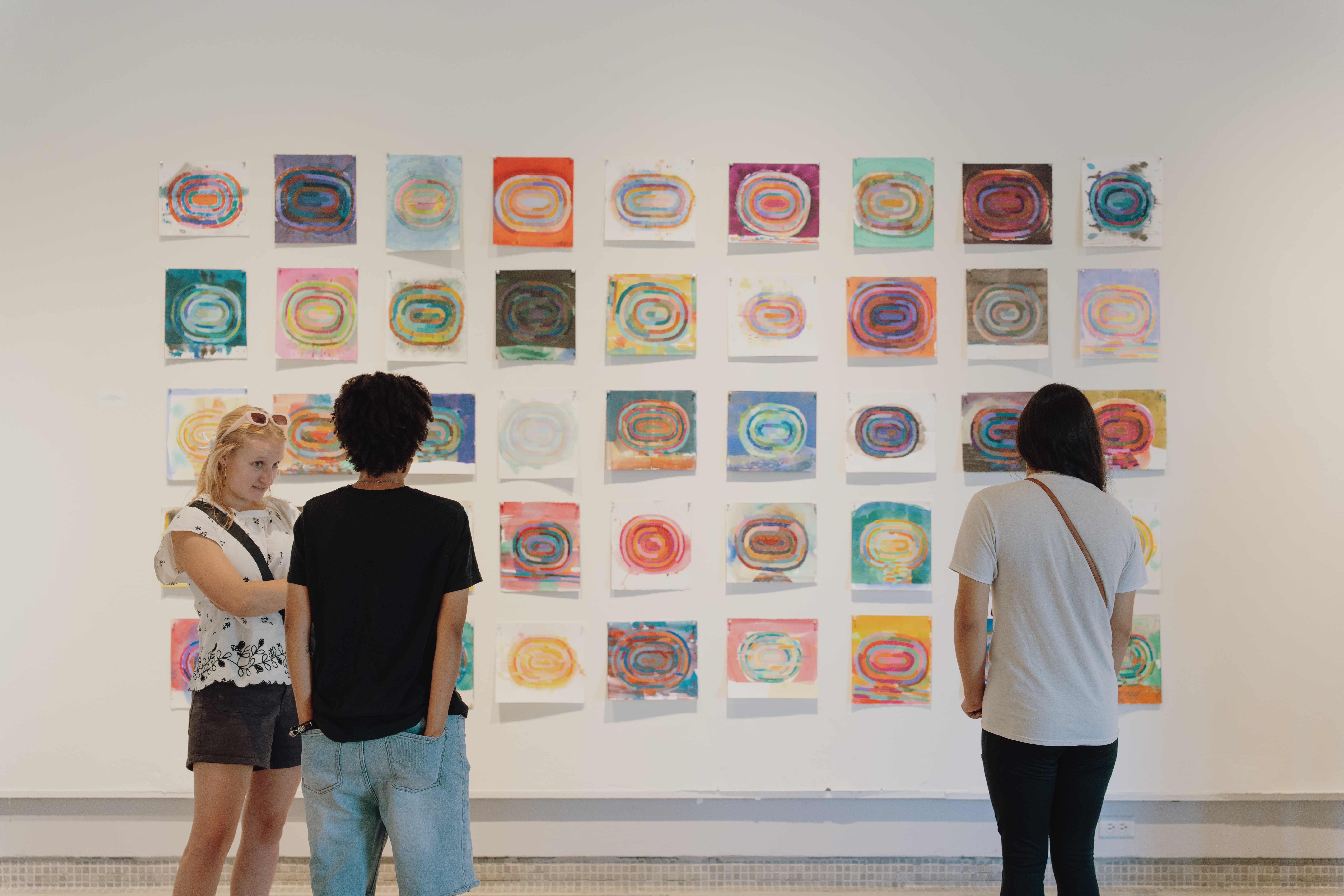a group of people looking at art on a wall