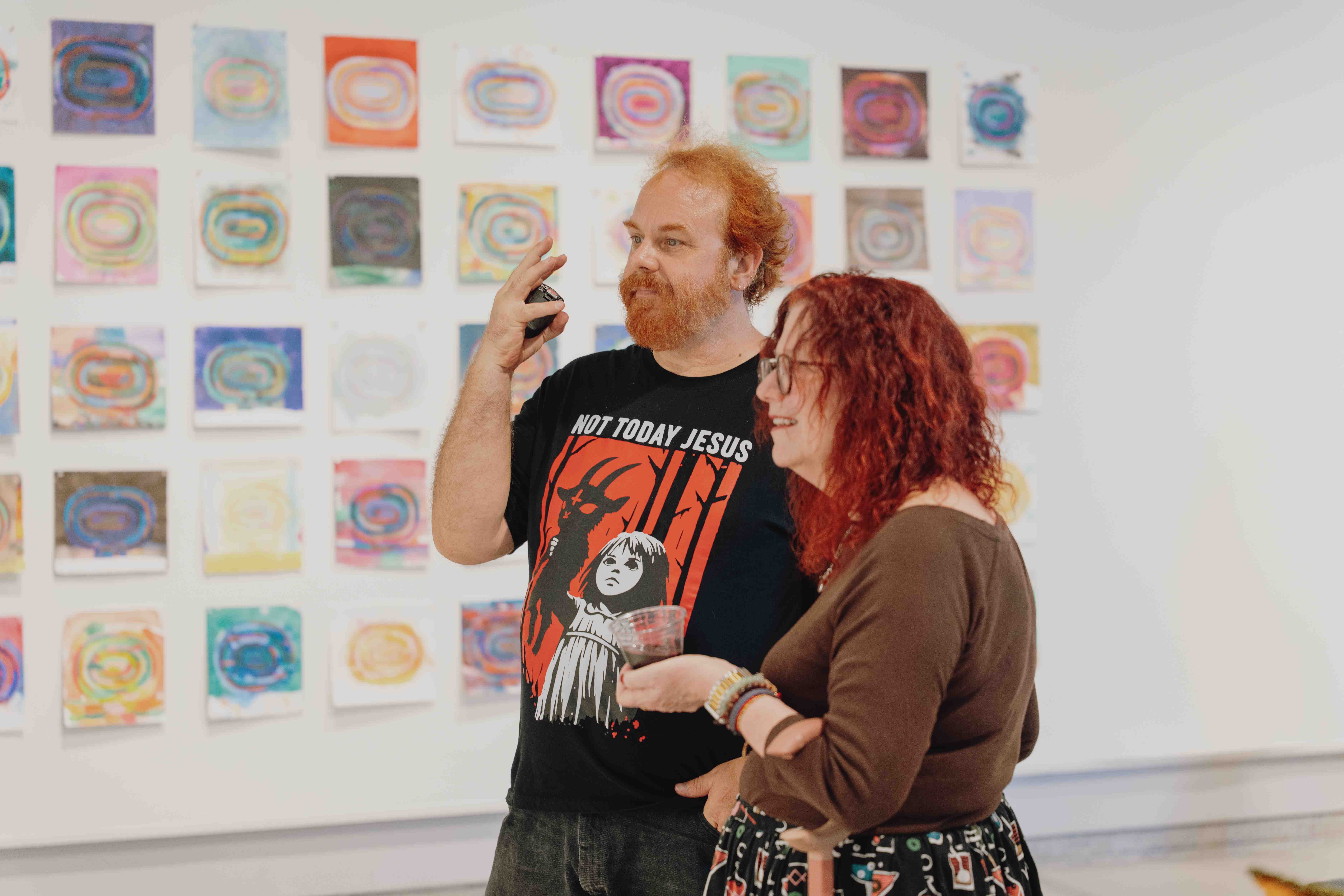 a person and person standing in front of a wall of art