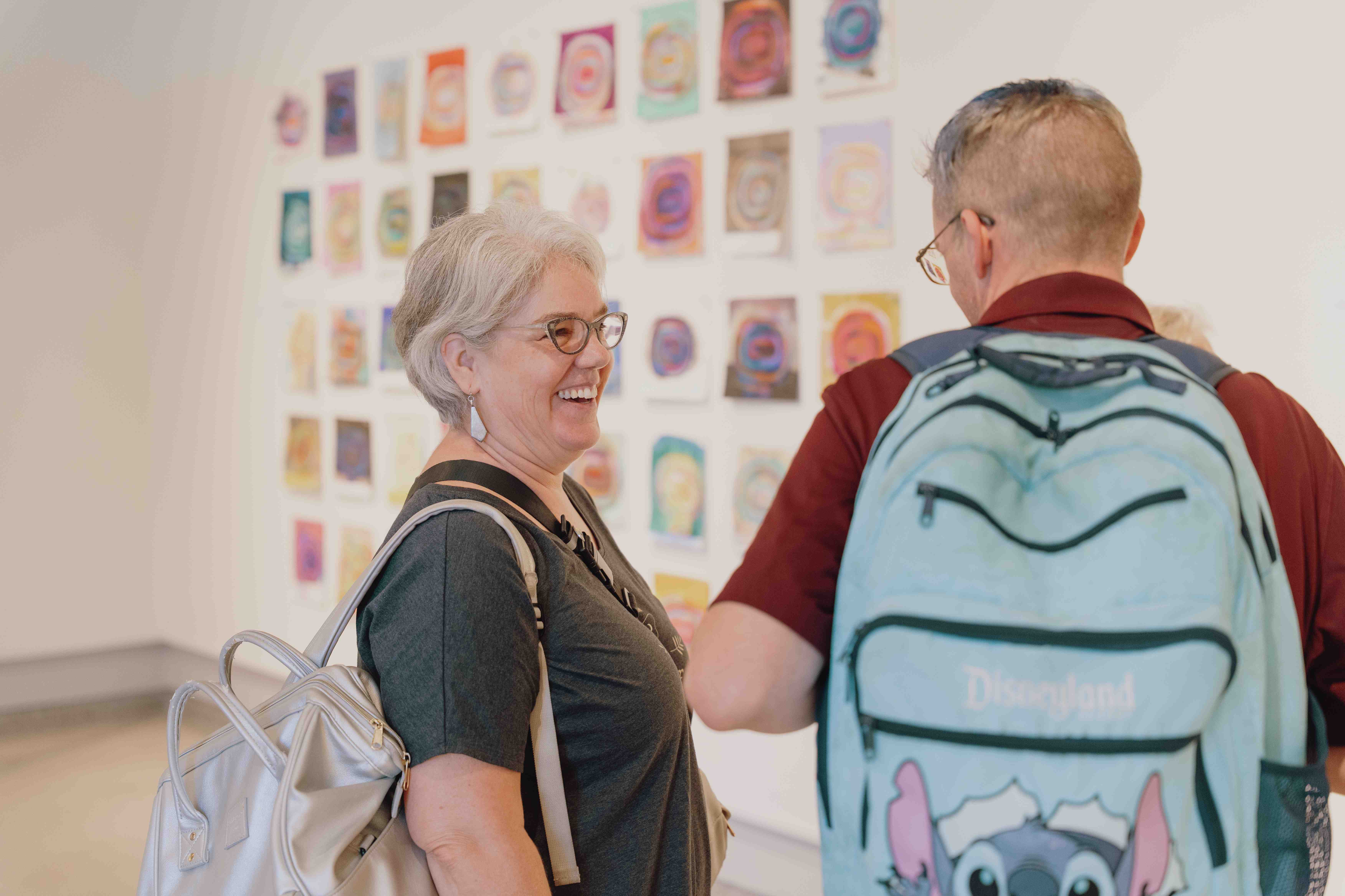 a person and person looking at pictures on the wall