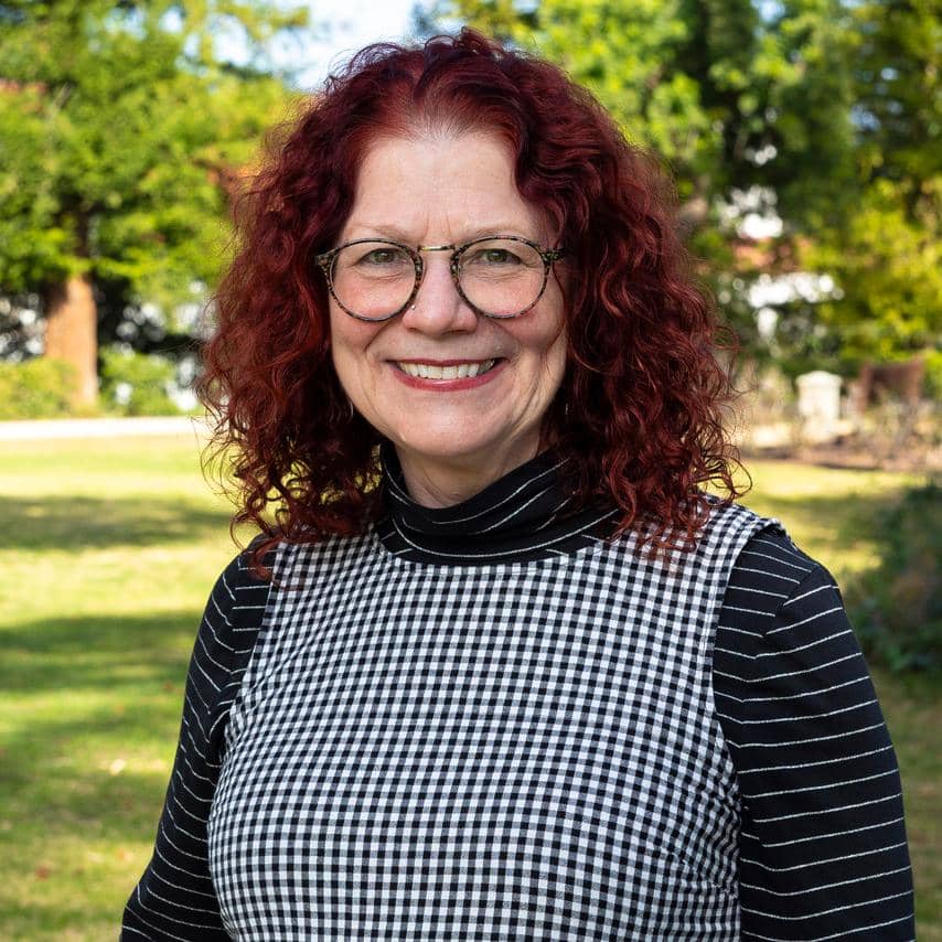 a person with red curly hair wearing glasses and a black and white checkered shirt