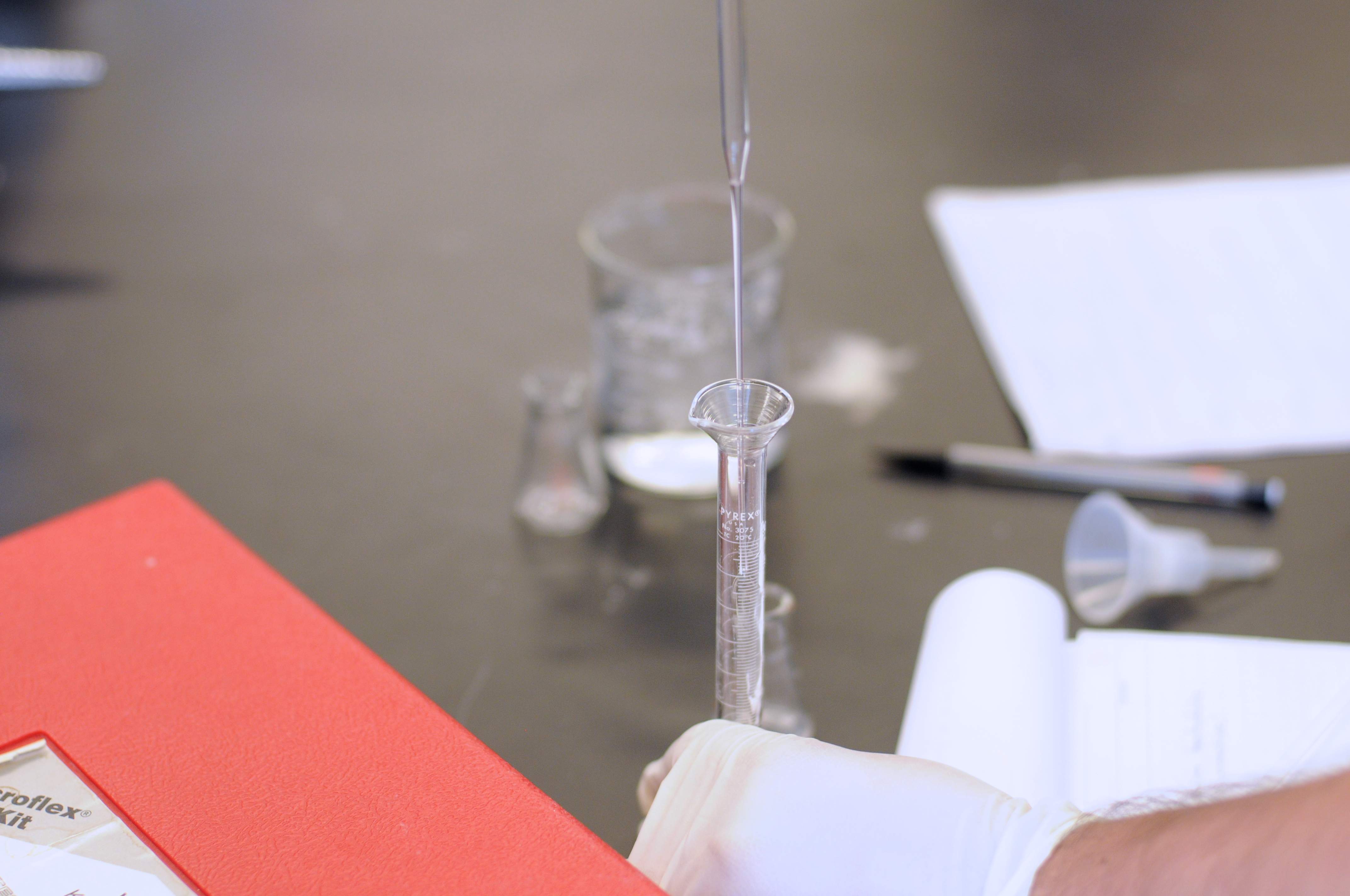a person holding a pipette over a beaker