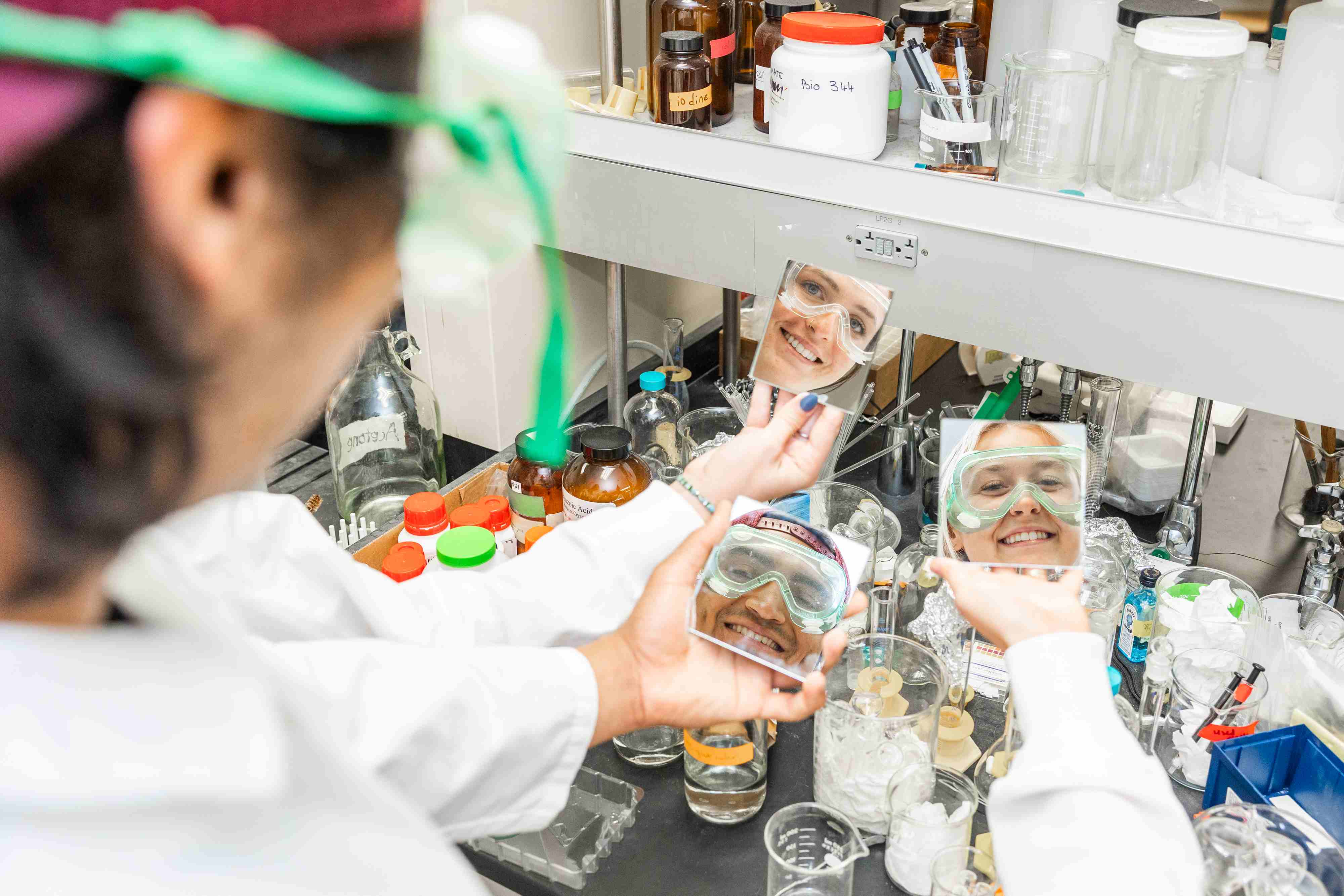 a person holding a mirror in front of a shelf with bottles