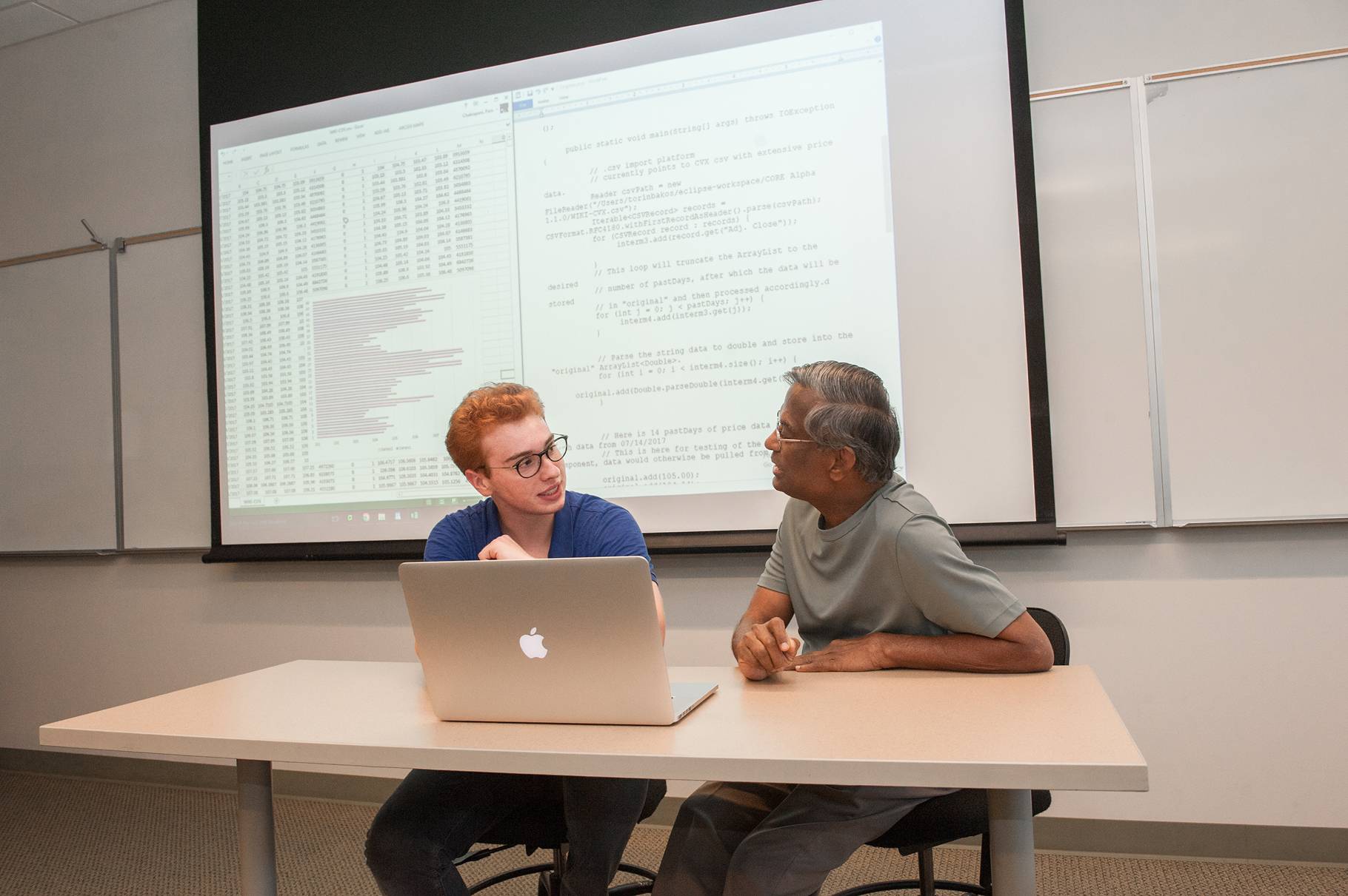 a person and person sitting at a table with a laptop