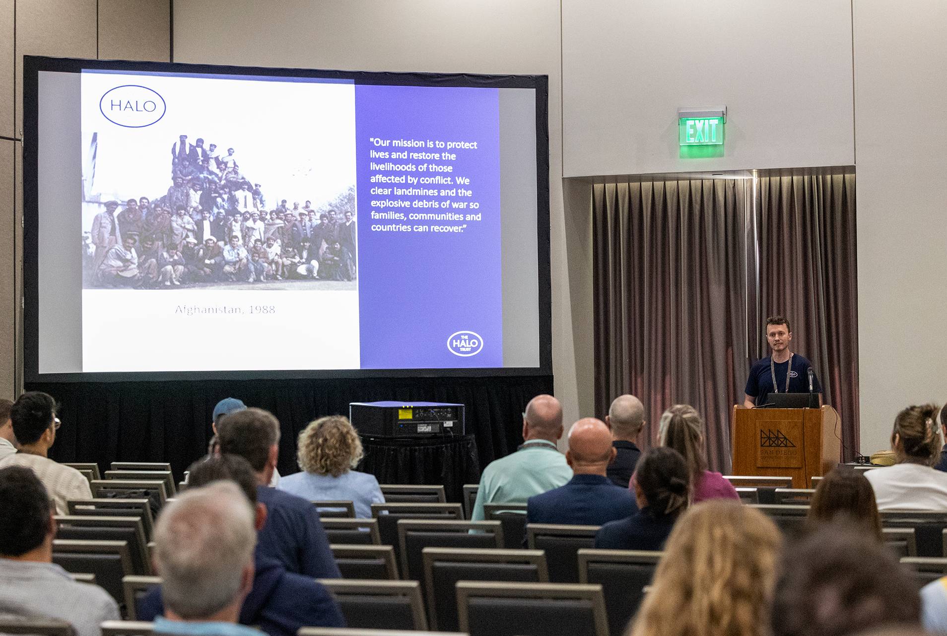 a person standing at a podium in front of a large screen