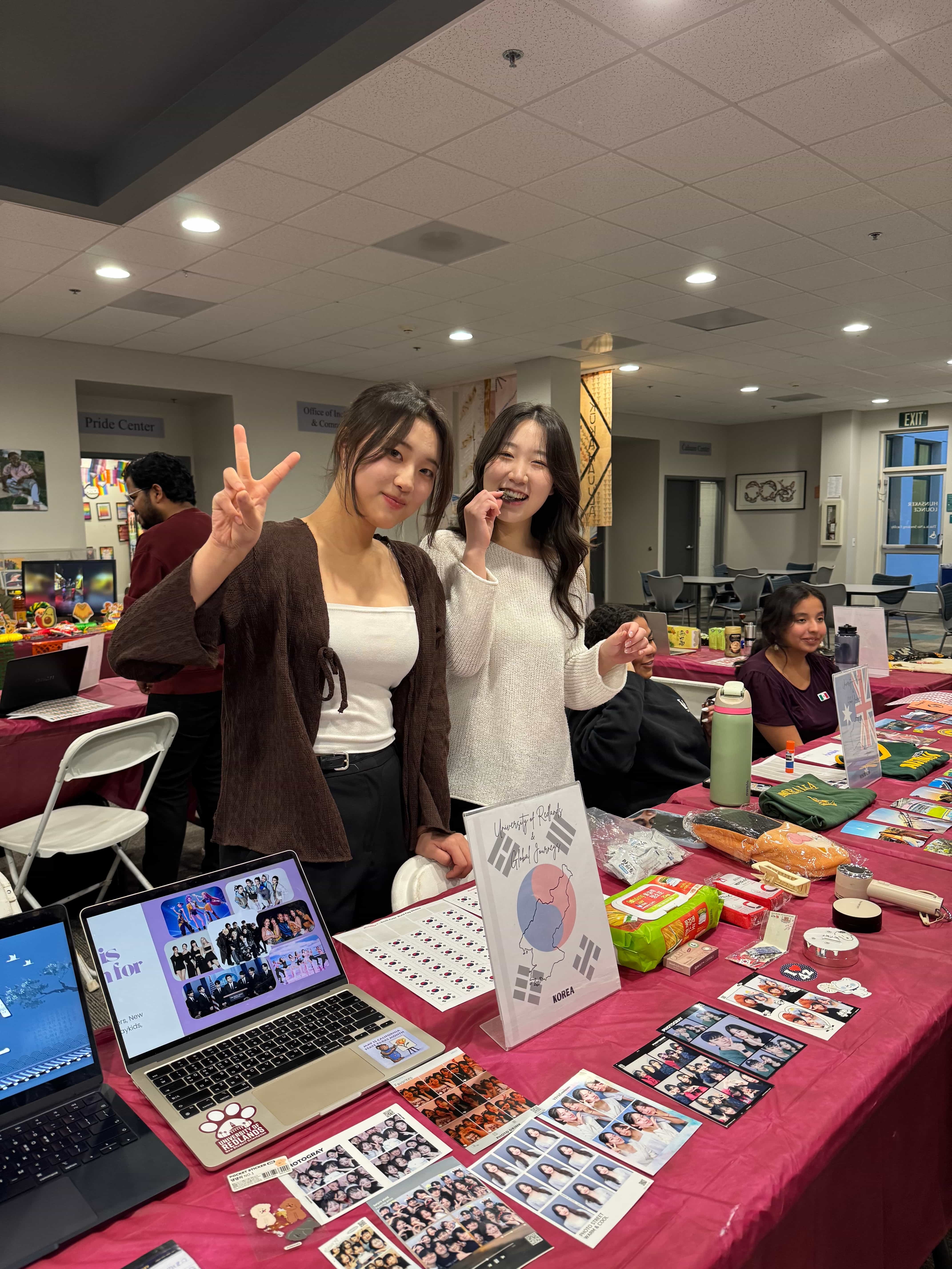 a group of women standing in front of a table with a table with food and a laptop