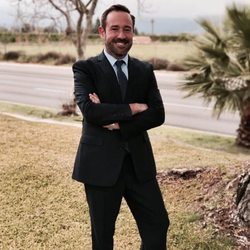 a person in a suit standing with his arms crossed