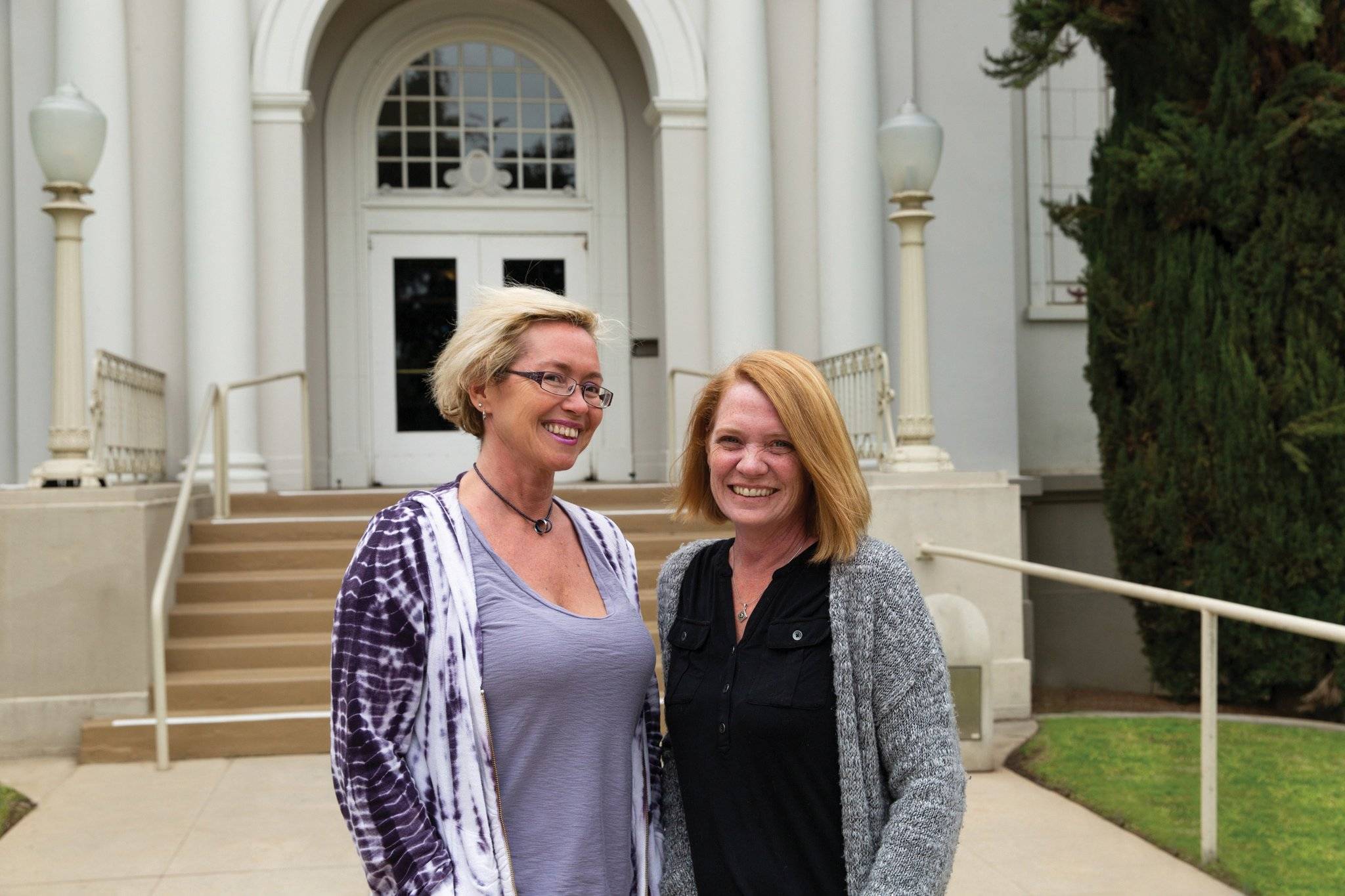 two women standing in front of a building