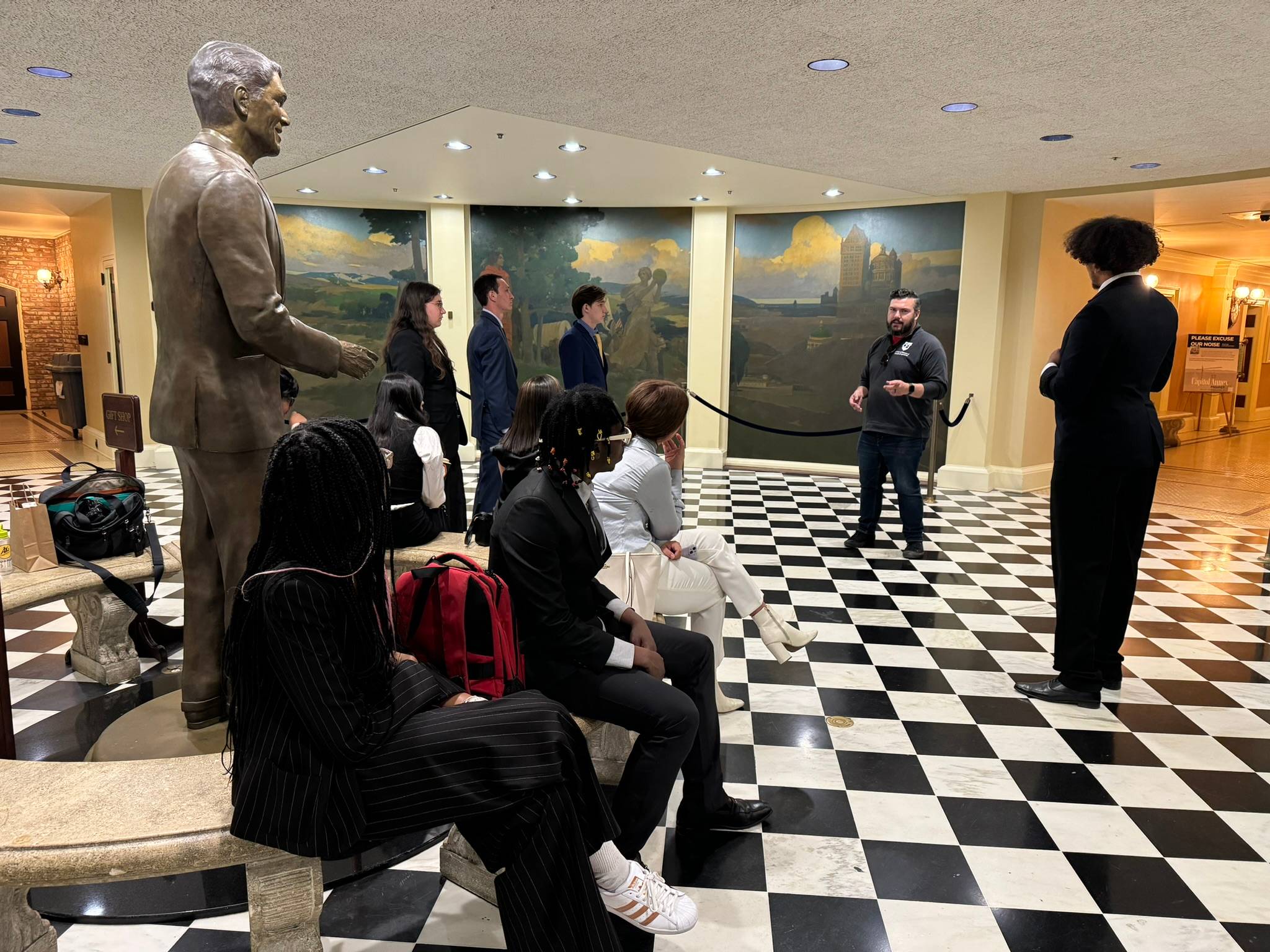 A group of students in a room with a statue of a person.