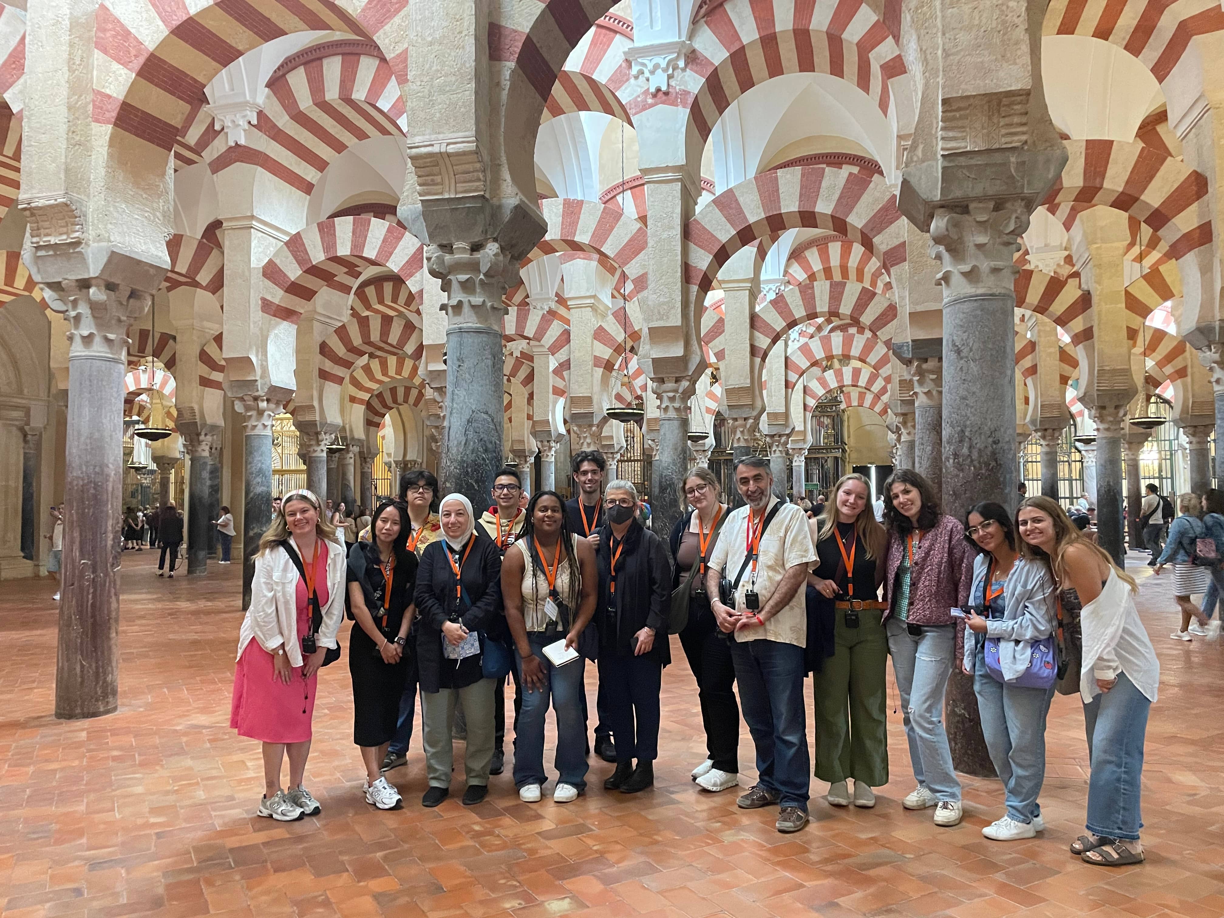a group of people posing for a photo in a large room with columns