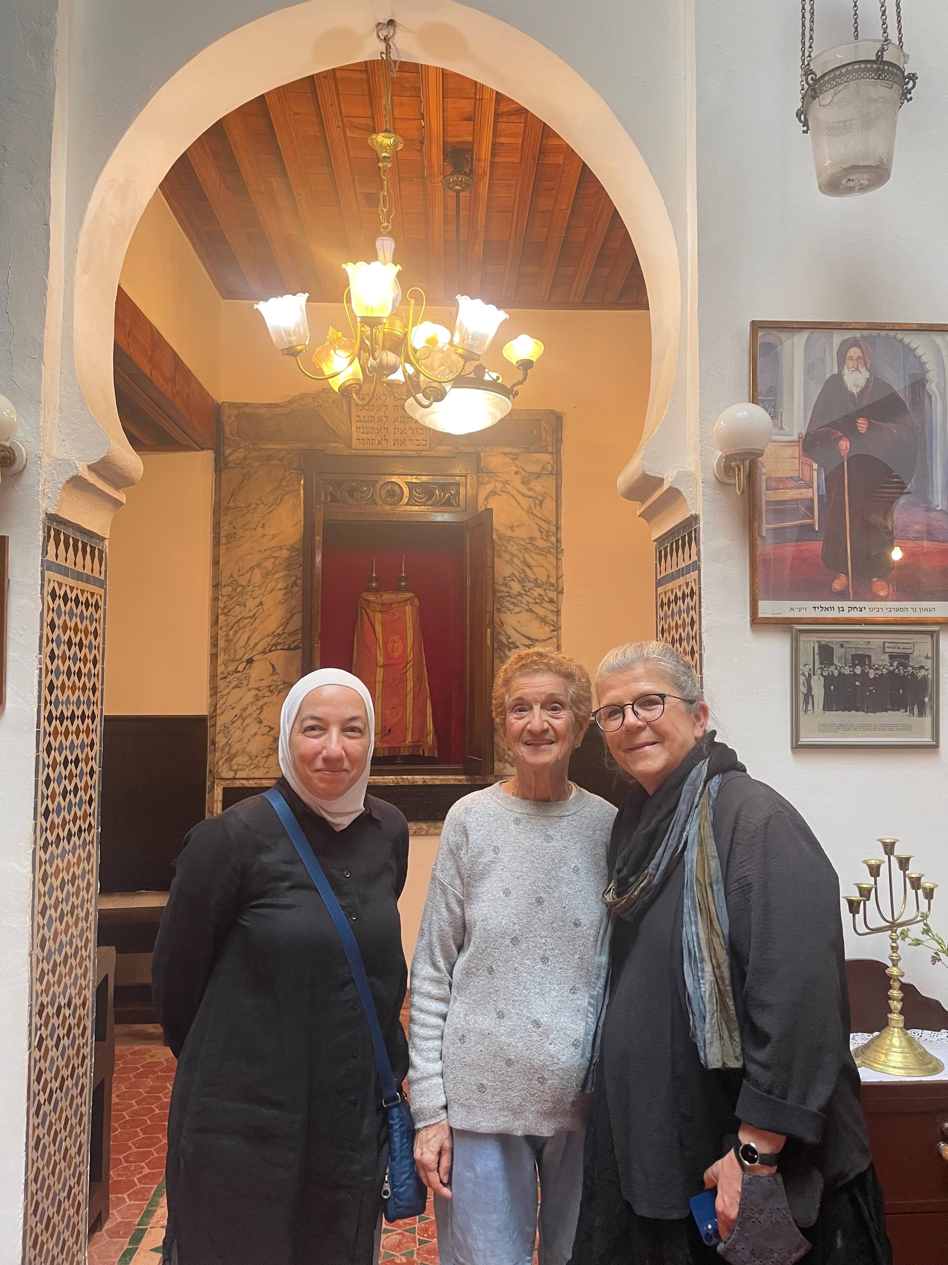 a group of women standing in a room with a chandelier