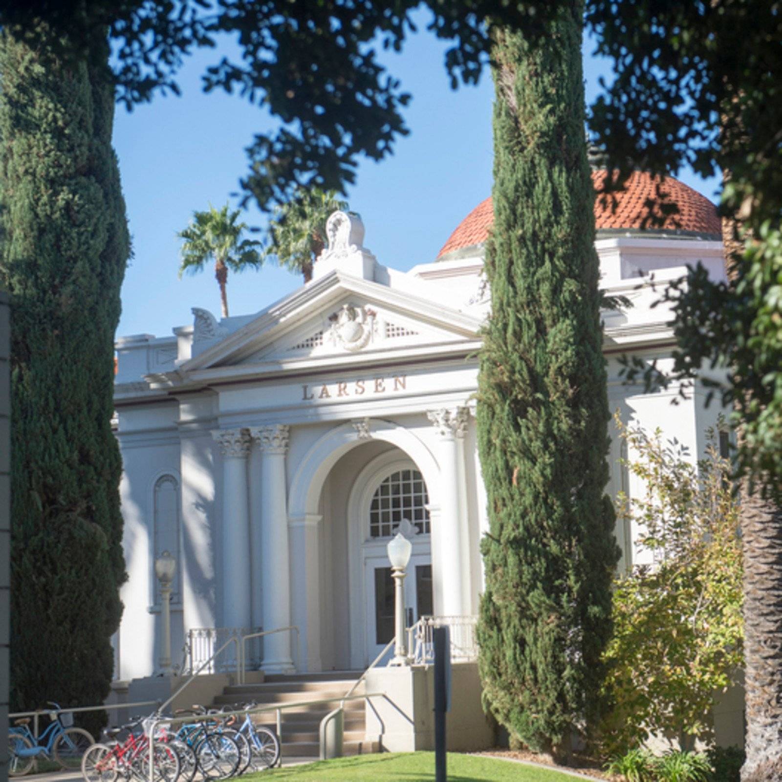 a white building with trees and a group of bicycles
