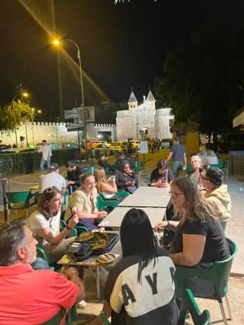 a group of people sitting at tables outside at night