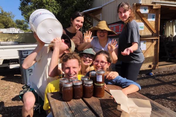 a group of people sitting at a table with jars of jam