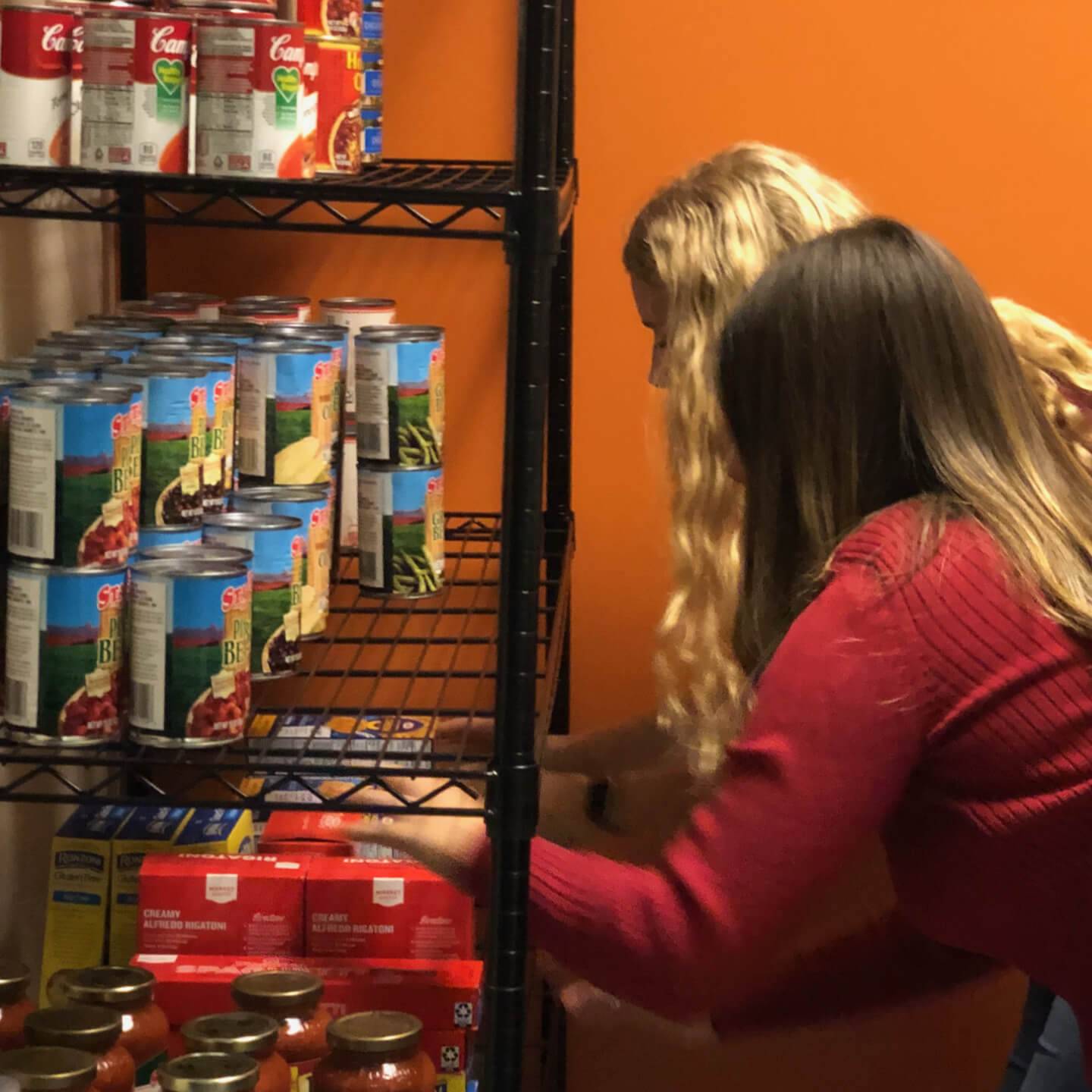 a group of women looking at cans on a shelf