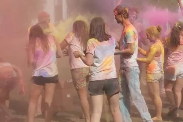 a group of people in white shirts with colorful powder around them