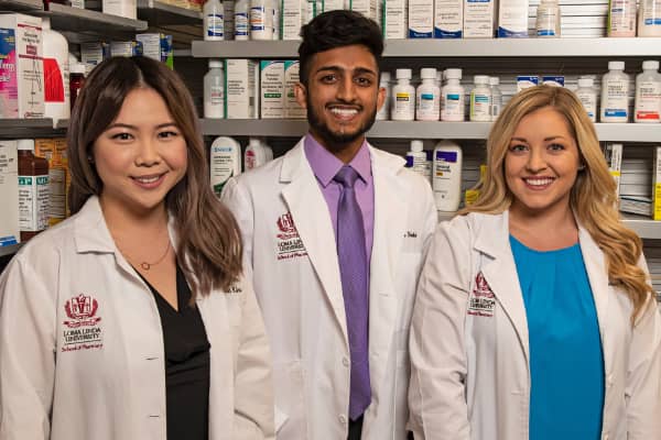 a group of people standing in front of a shelf of medicine