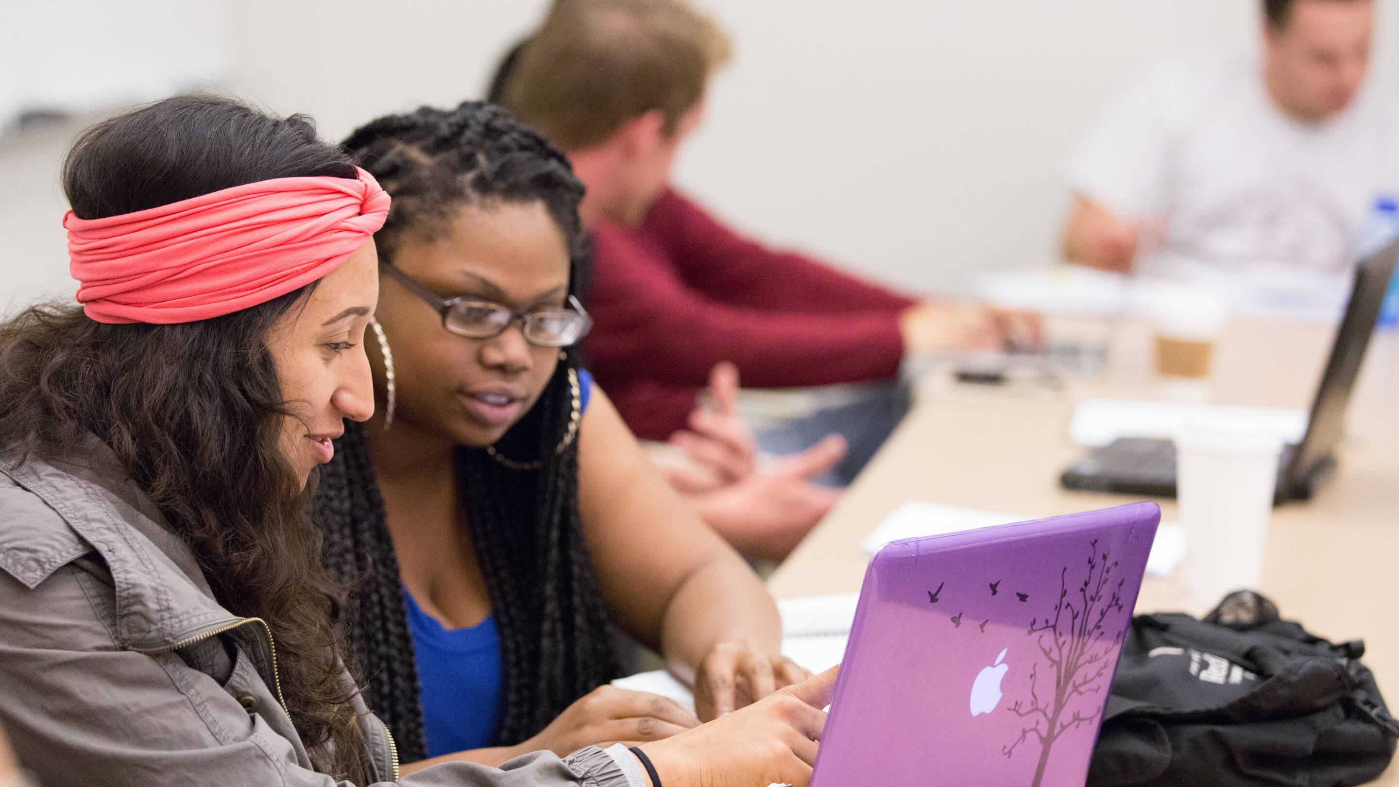 a group of people looking at a laptop
