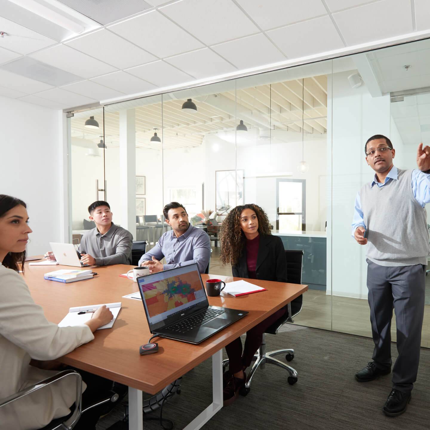 a person standing in front of a group of people around a table
