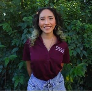 a person smiling in front of a bush