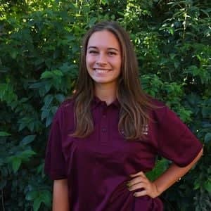 a person smiling in front of bushes