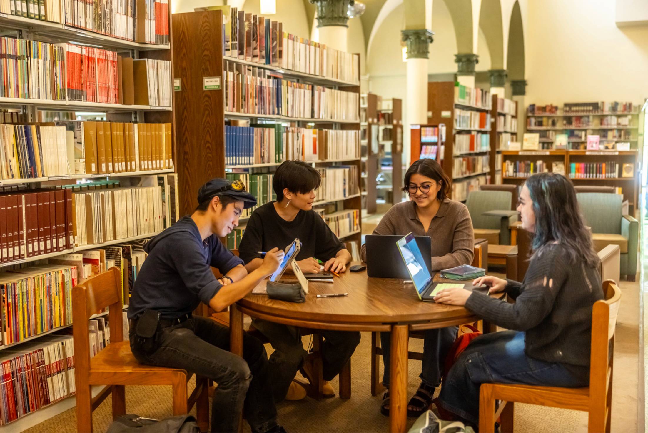 a group of people sitting around a table with laptops