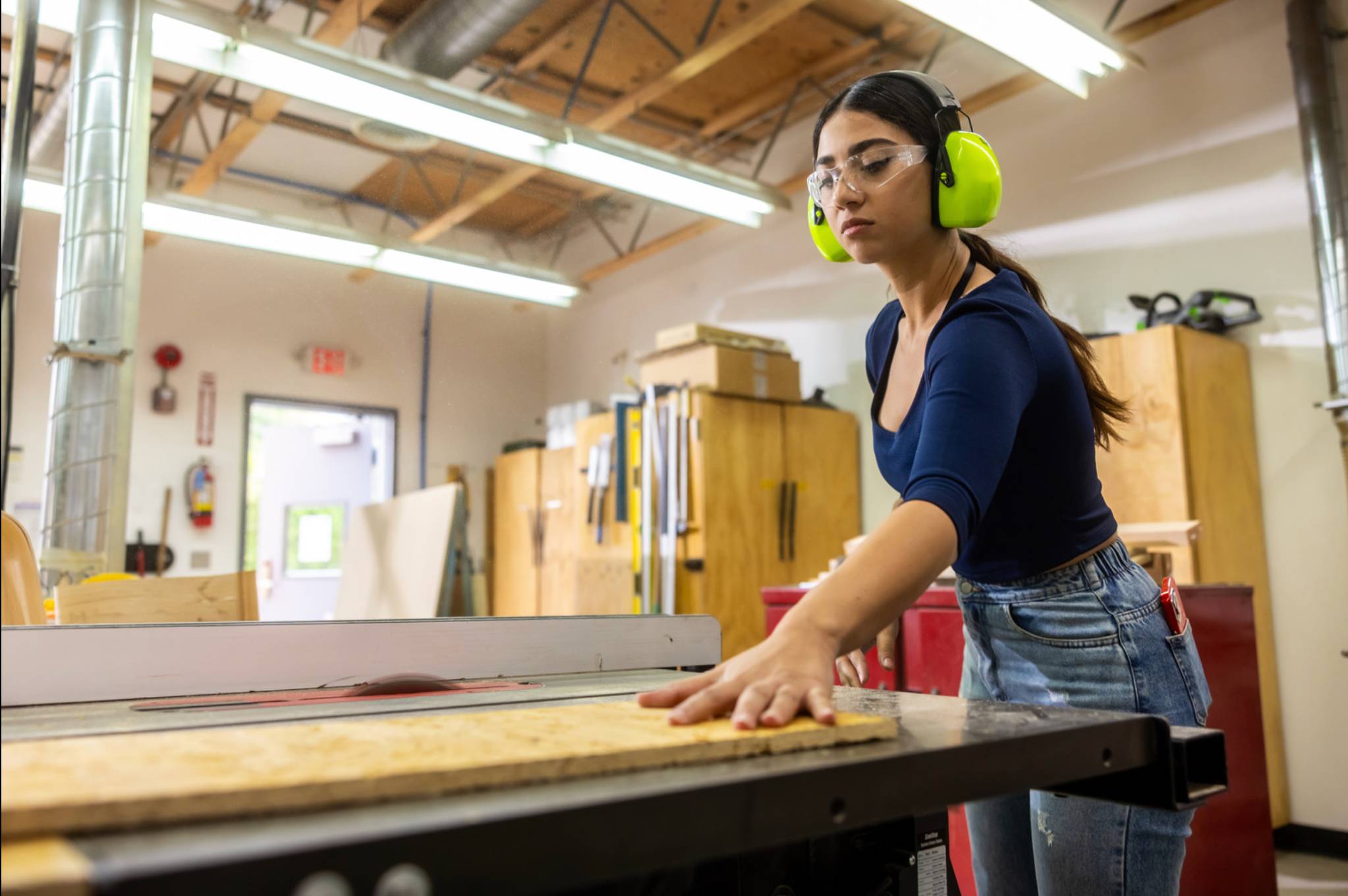 a person wearing ear muffs and working on a woodworking machine