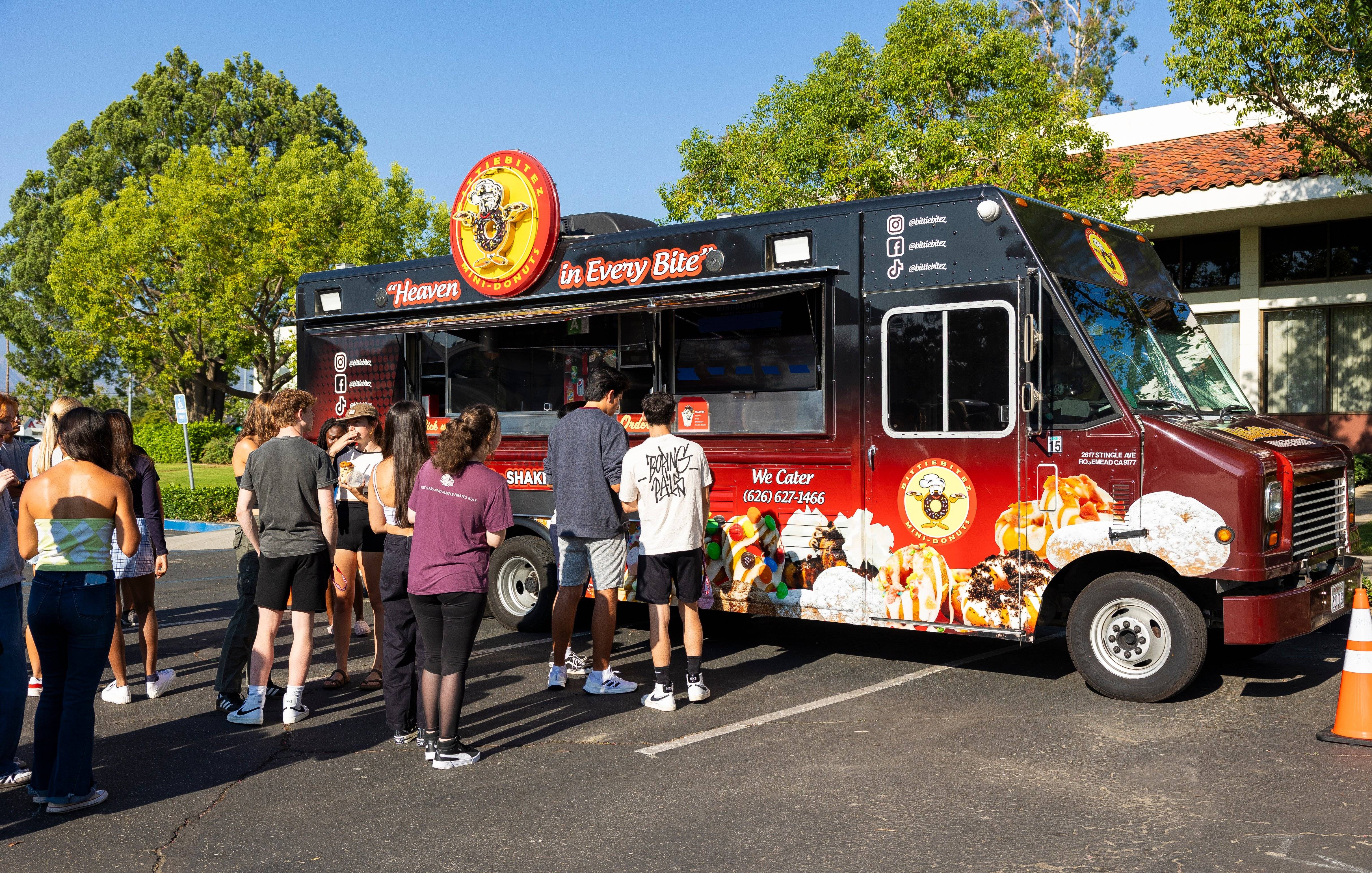 a group of people standing in front of a food truck
