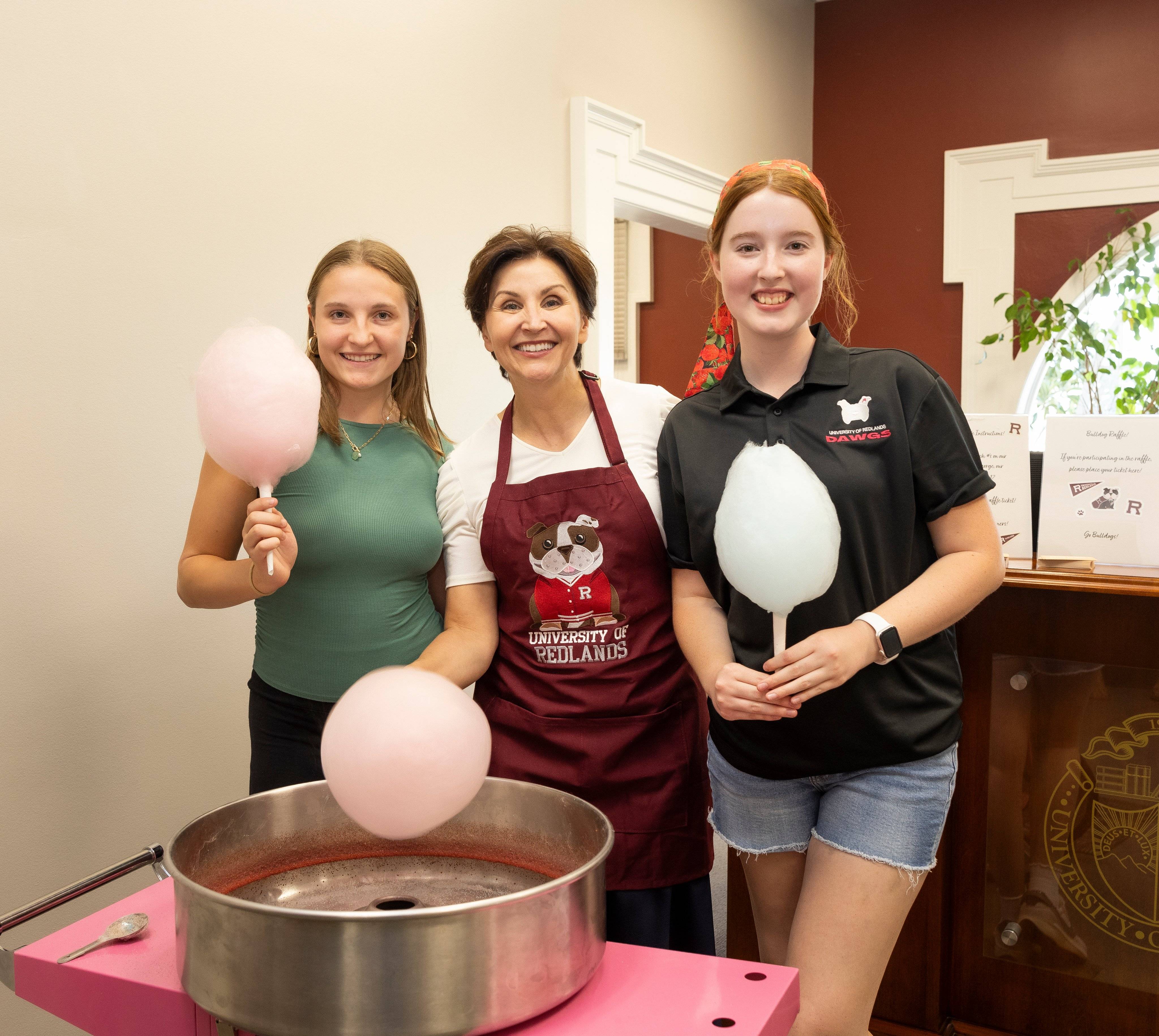 a group of women standing next to a machine with cotton candy
