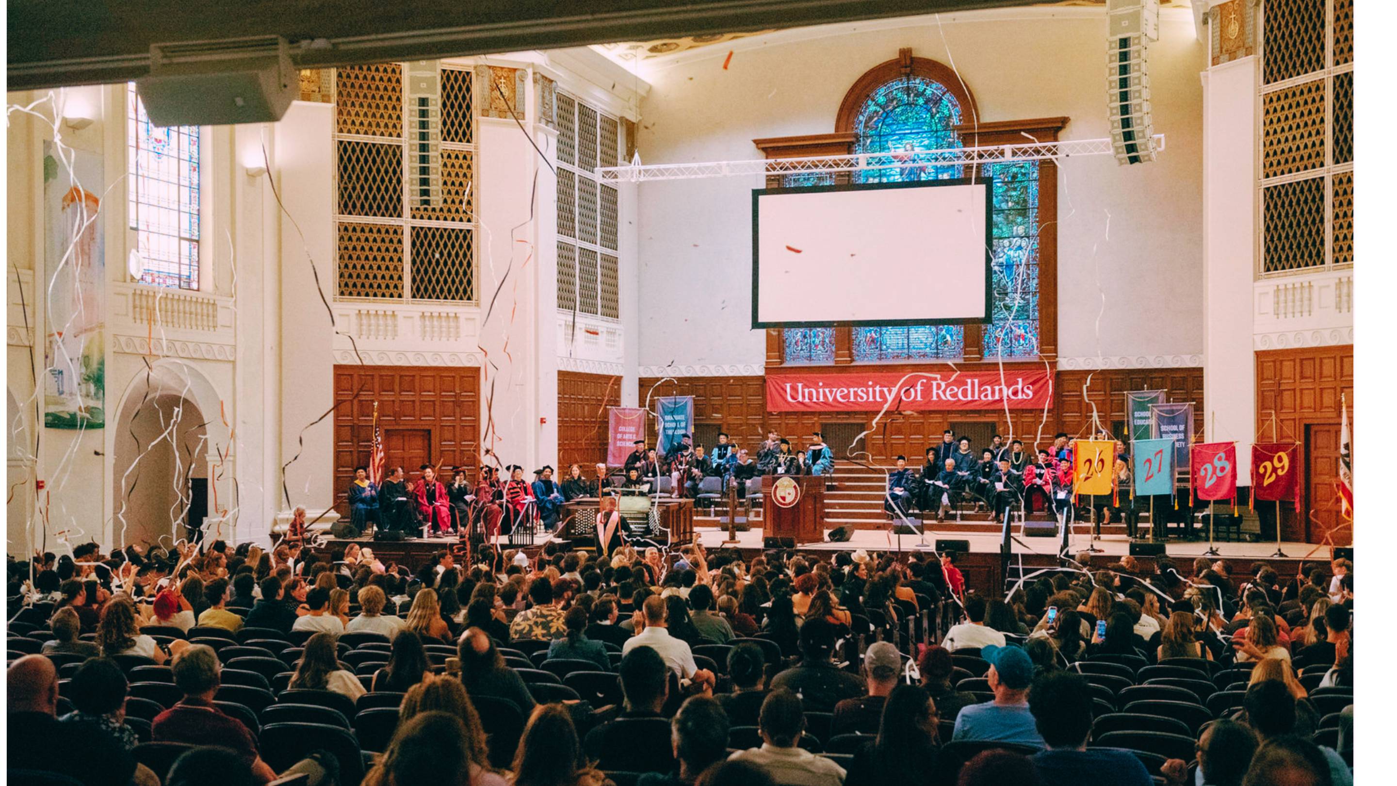 a group of people on a stage in a large room with a large screen