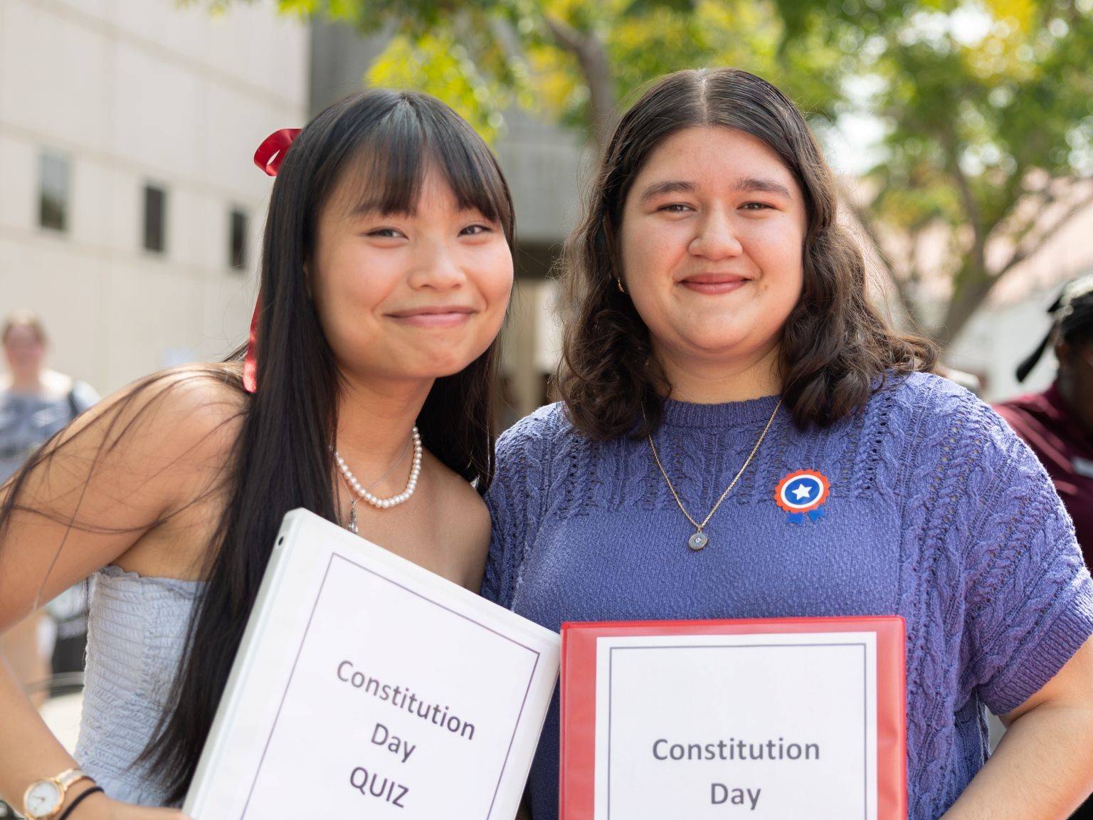 Two Pi Sigma Alpha members holding Constitution Day quiz materials on campus