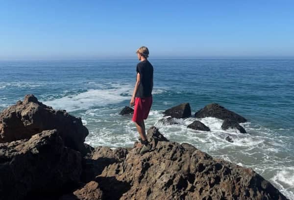 a person standing on a rock by the ocean