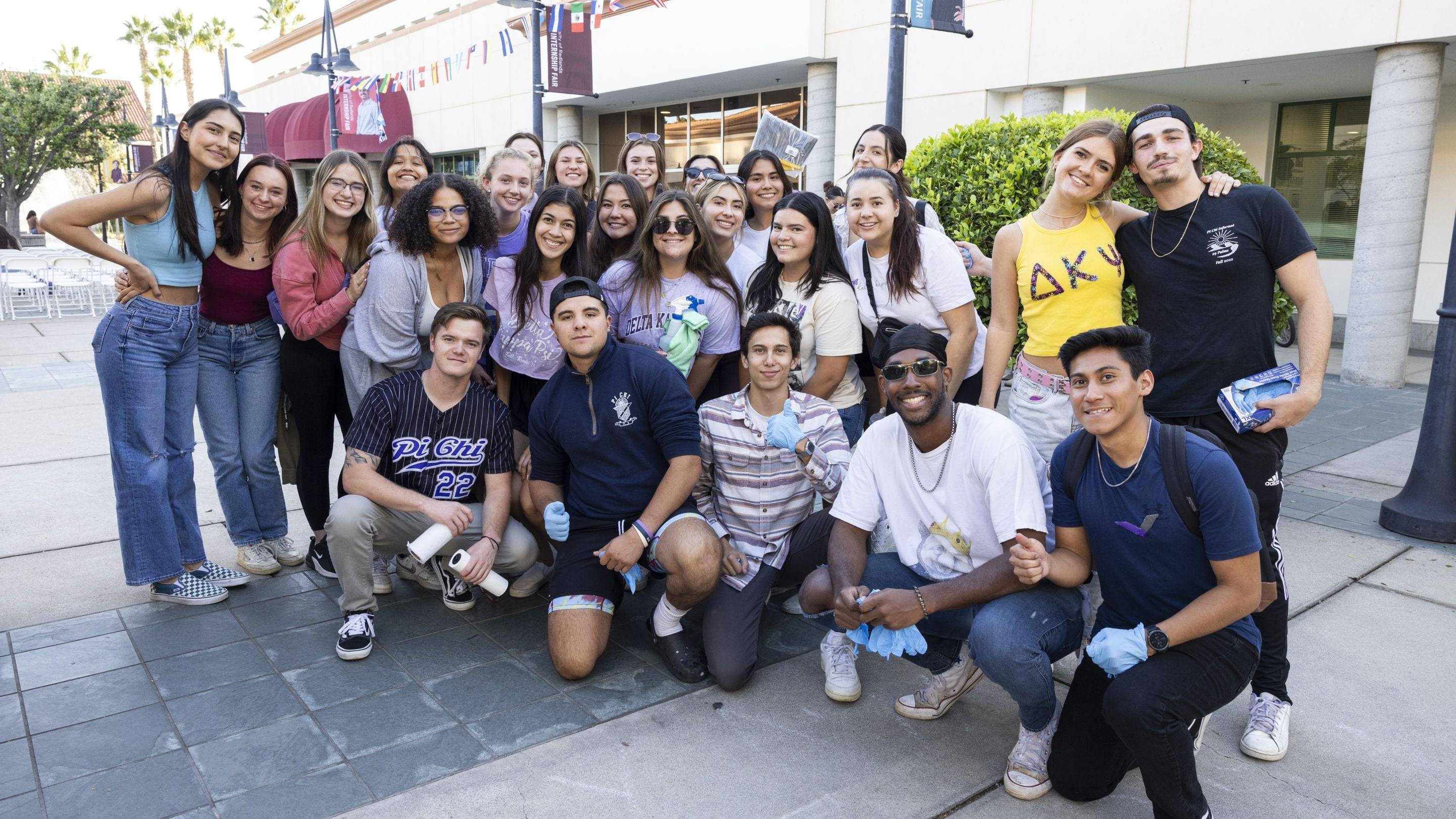 A large group of University of Redlands Greek life students pose together outdoors during a campus event.