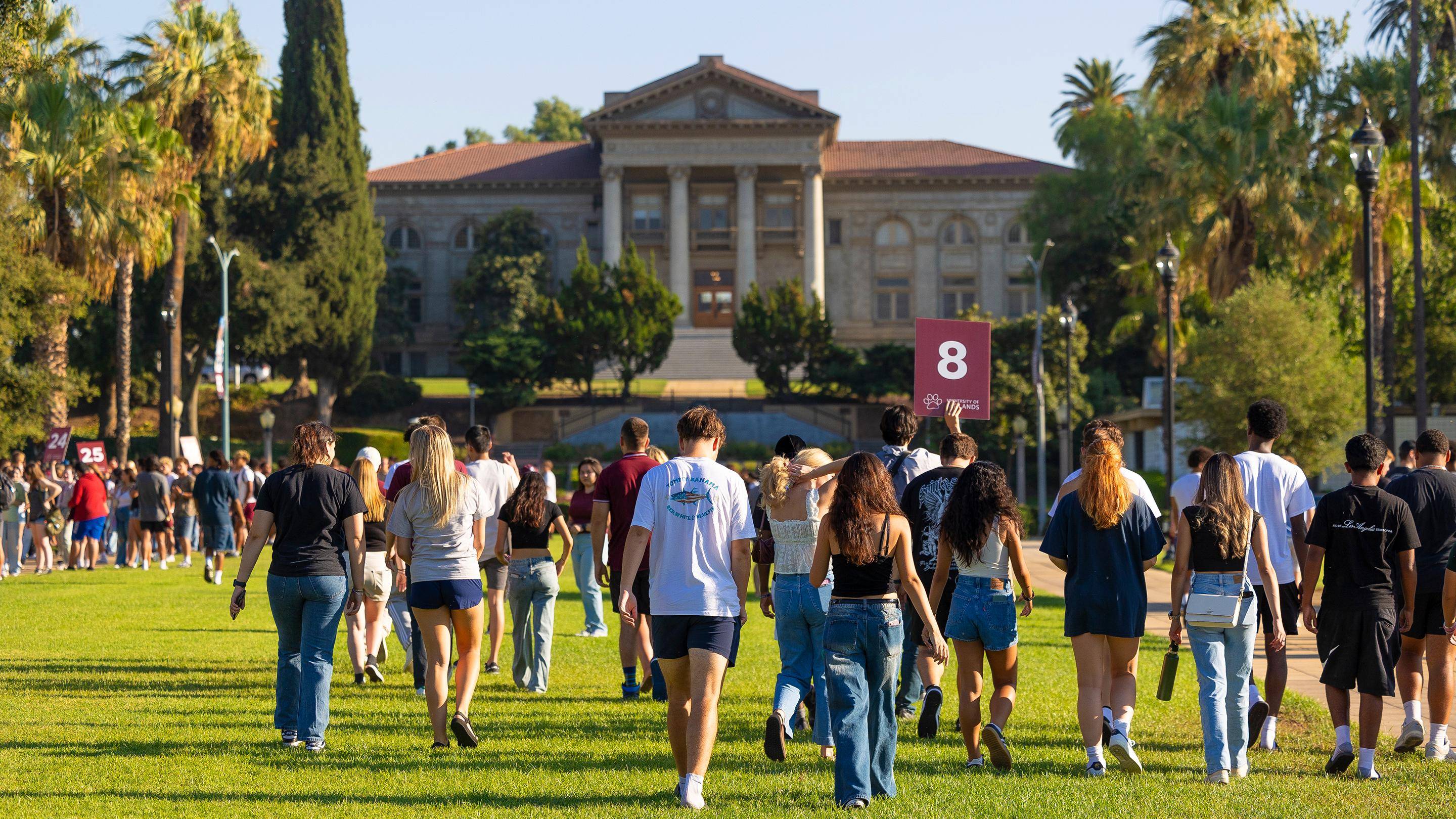 a group of people walking on grass in front of a building
