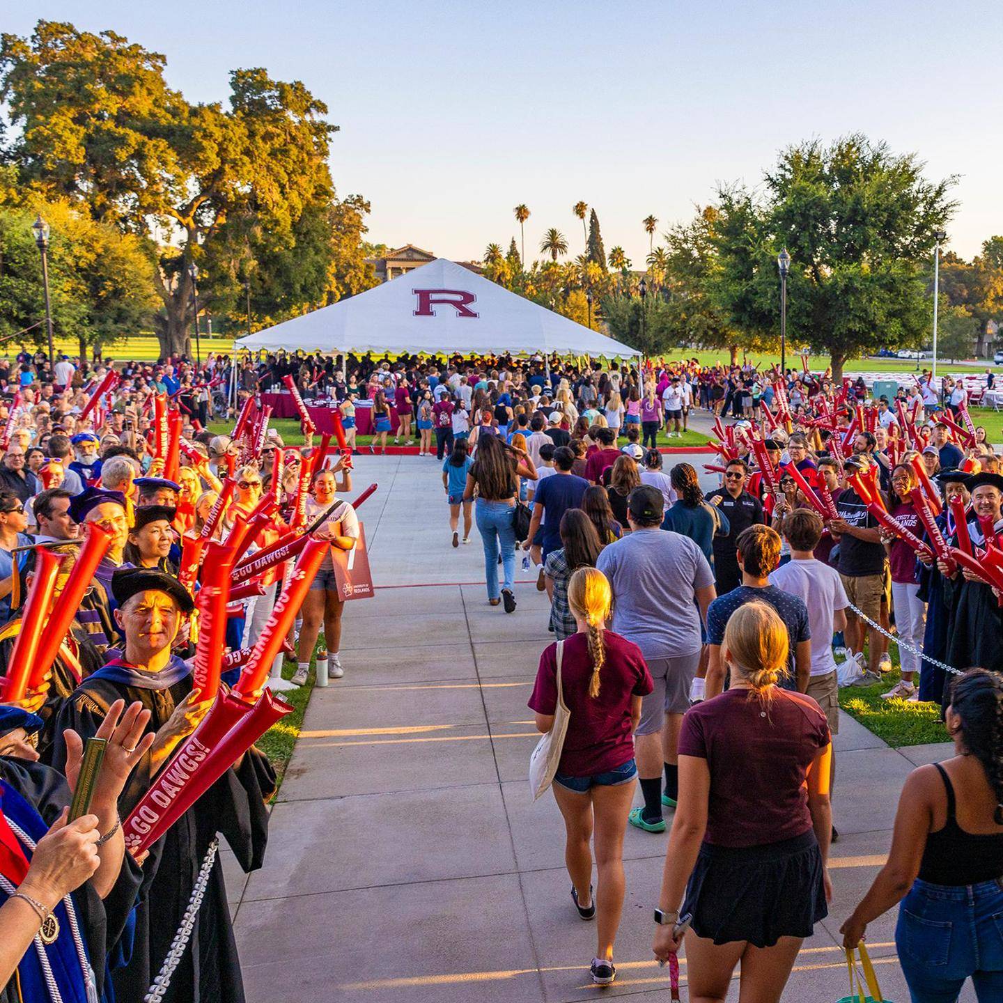 a group of people walking on a sidewalk with a white tent