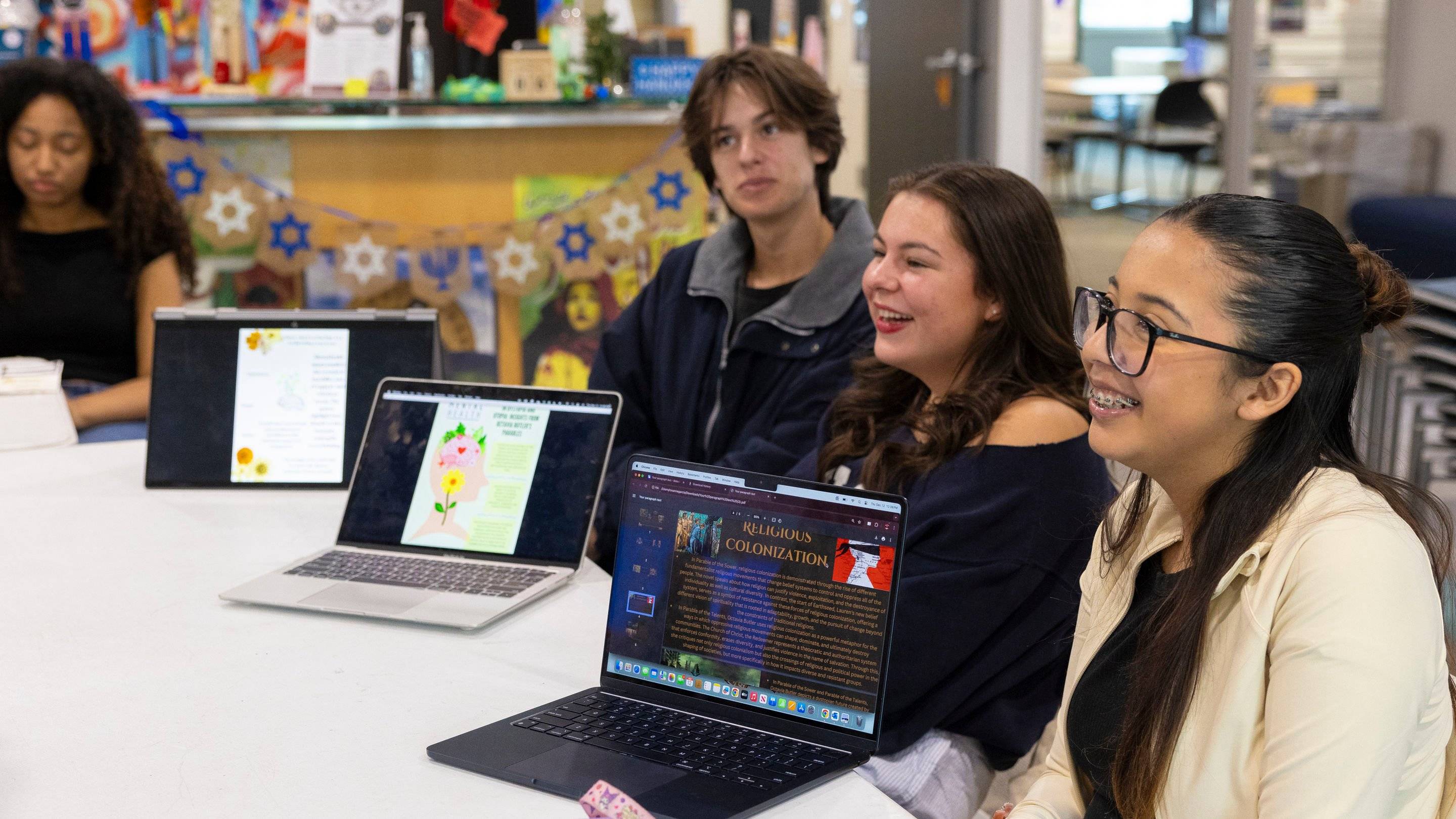 a group of people sitting at a table with laptops