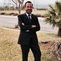 a person in a suit standing with his arms crossed