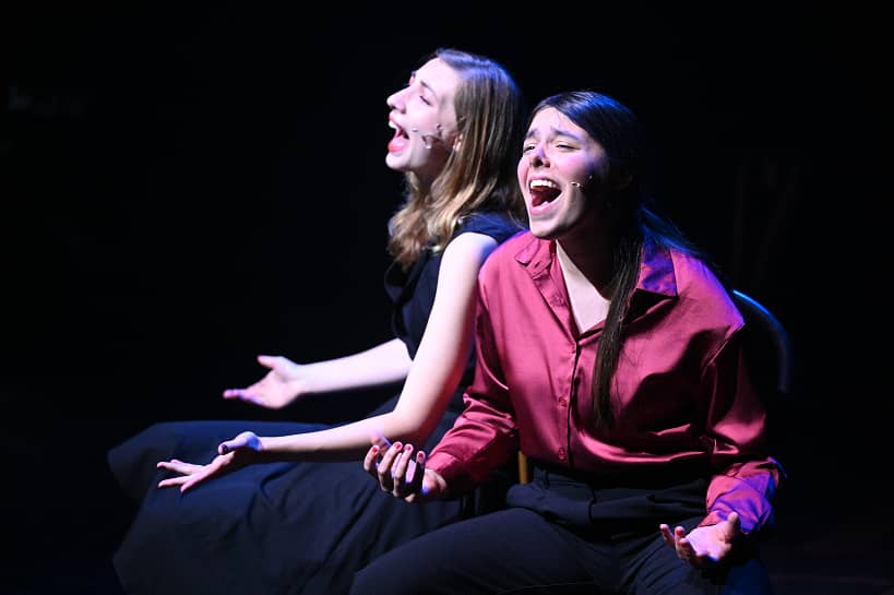 two women sitting on a stage
