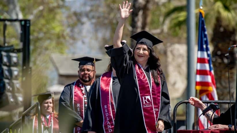 a person in graduation gown waving