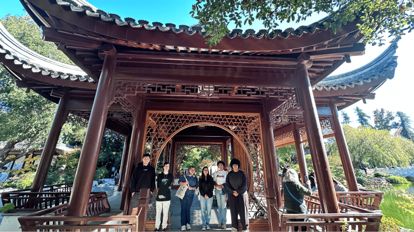 a group of people standing under a wooden structure