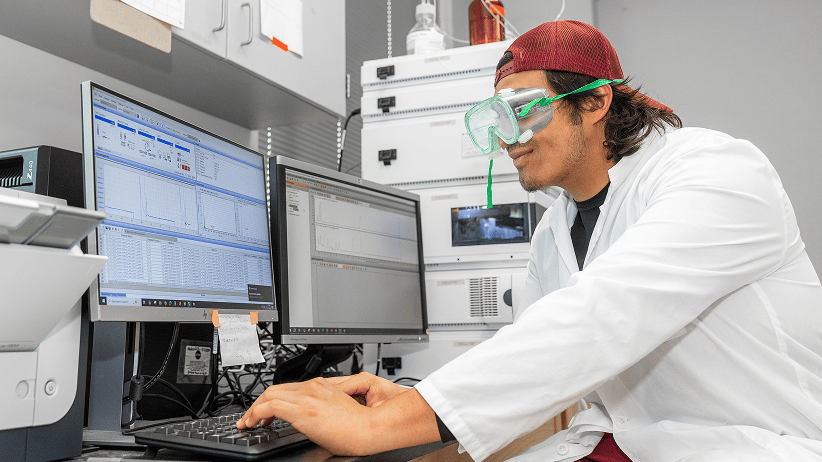 a person wearing goggles and a red hat working on a computer