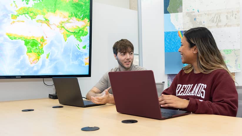 a person and person sitting at a table with laptops