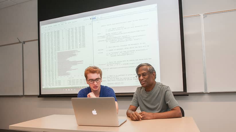 a person and person sitting at a table with a laptop
