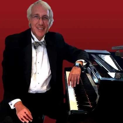 a man in a suit and bow tie playing a piano