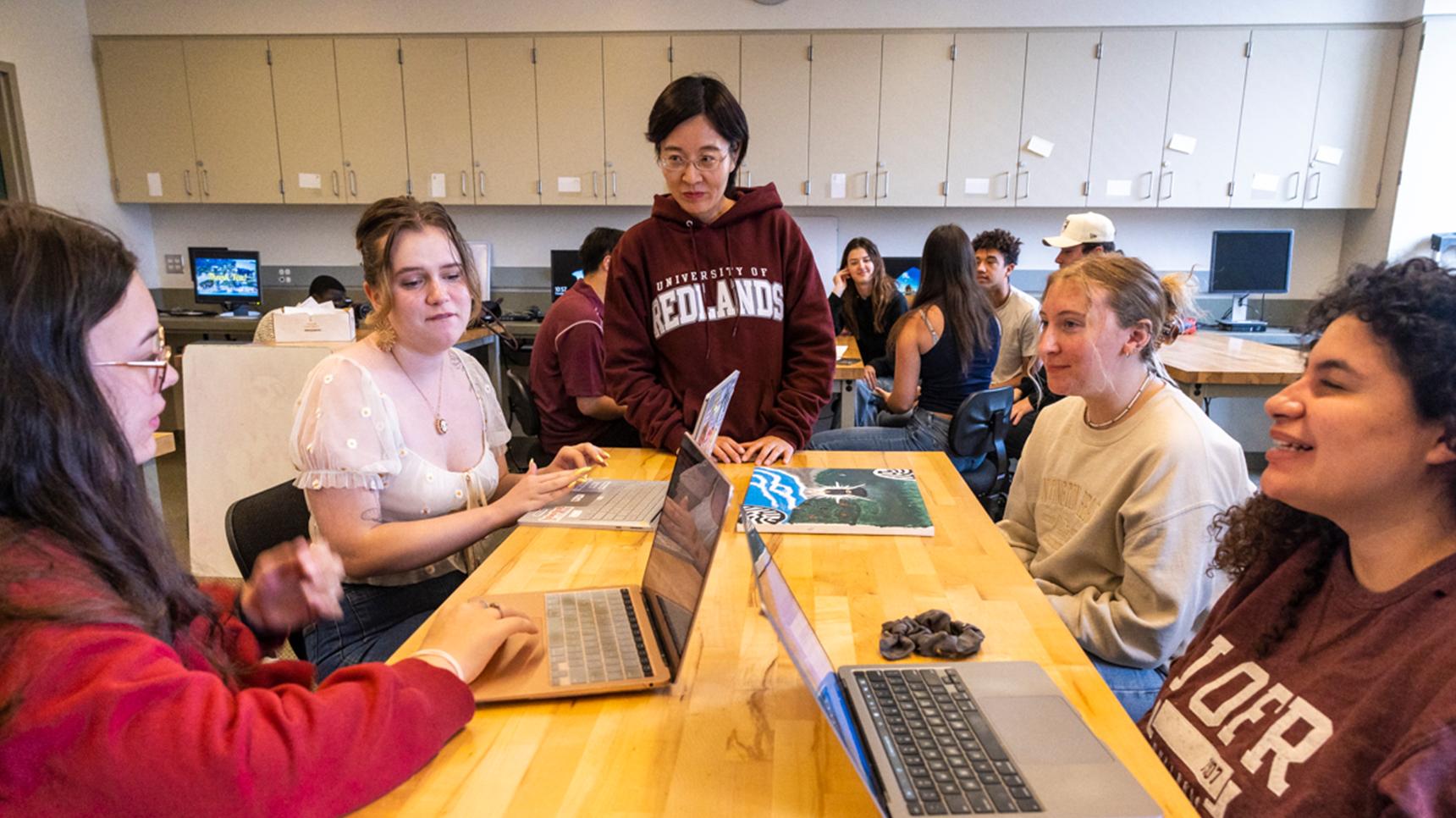 a group of people sitting around a table with laptops