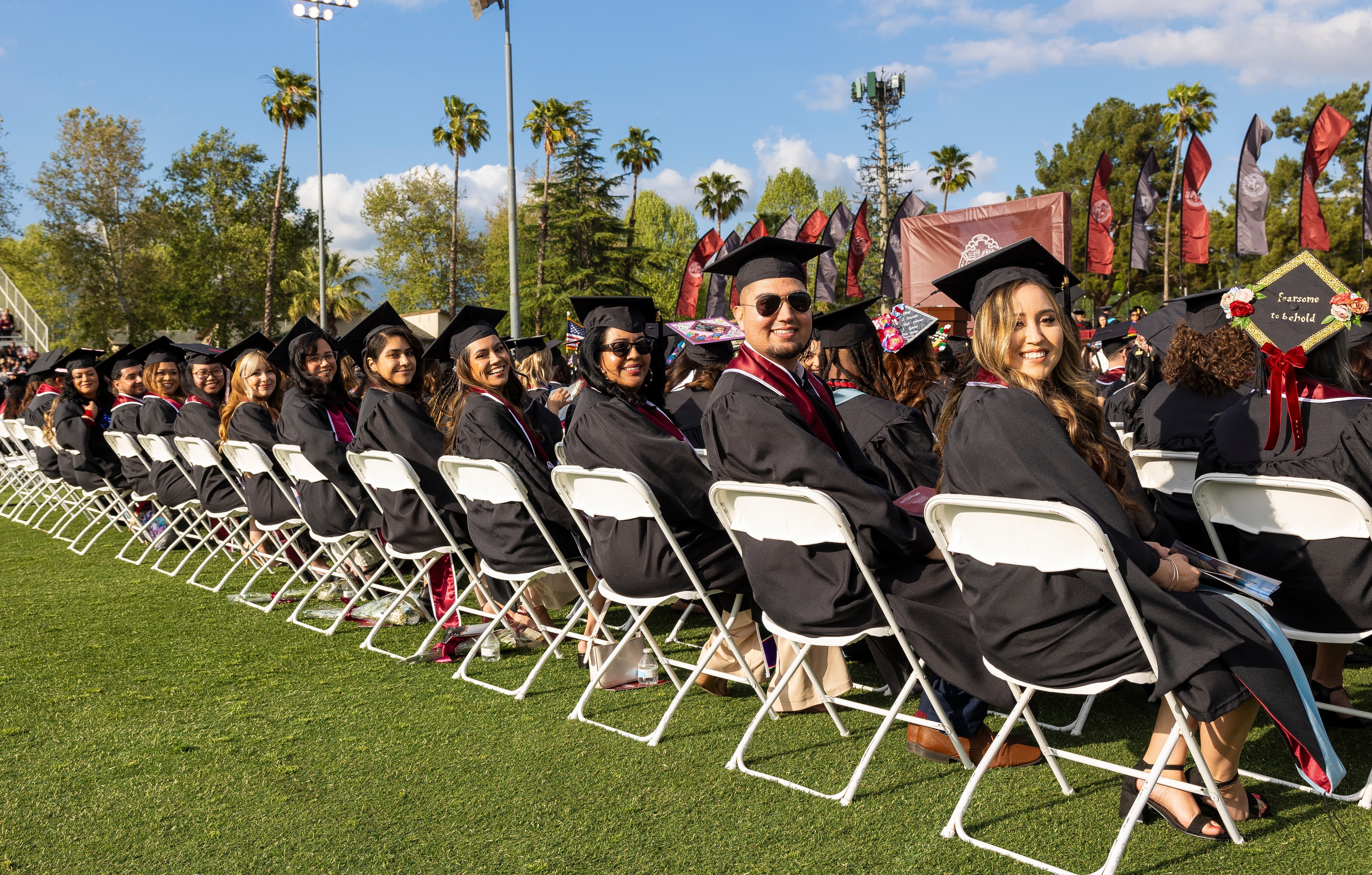 a group of people in graduation gowns and caps sitting in chairs